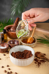  The process of making a homemade coffee scrub for skin care, adding oil. Eco-friendly cosmetics, vertical photo