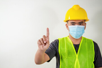 Engineer in medical mask touching transparent screen display with selectived focus on finger. Constructtion Concep.