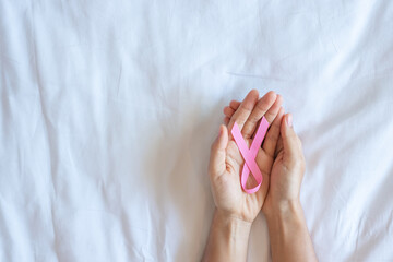 October Breast Cancer Awareness month, adult Woman  hand holding Pink Ribbon on pink background for supporting people living and illness. International Women, Mother and World cancer day concept