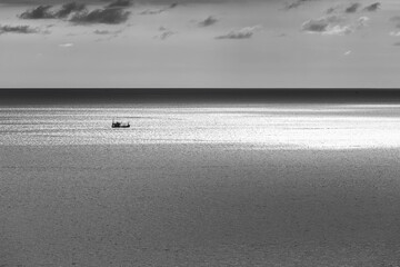 Shining sea with the fishing boat when sundown in black and white