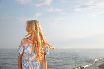 Fototapeta na wymiar Beautiful young woman near sea on sunny day, space for text