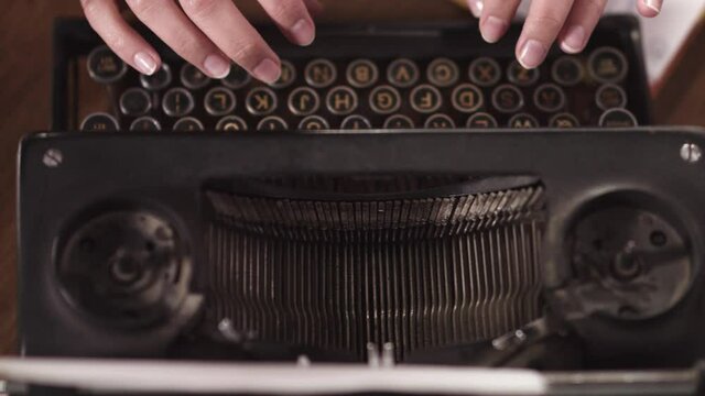 slow motion close up shot of a woman typing on old vintage typewriter, change focus, from above handheld. writer, news, retro media concept