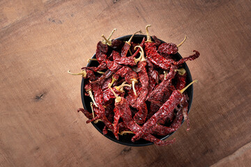 red chillis or chilli or laal mirch or mirchi in a wooden bowl on wooden dark theme