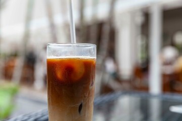 Iced cappuccino in a glass with straws on a table at a trendy cafe