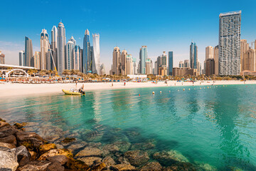 Luxurious and spectacular sandy beach with vacationers in the Dubai Marina and JBR area with tall...