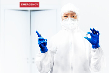 Health worker woman with a protective suit and gloves holding covid 19 vaccines