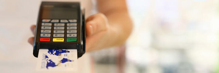 Male hand holding pos terminal with credit bank card closeup