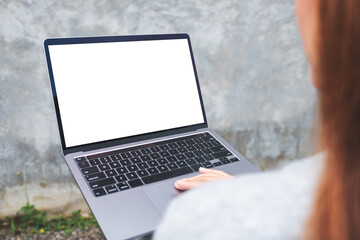 Top view mockup image of a woman using and typing on laptop computer with blank white desktop screen n the outdoors