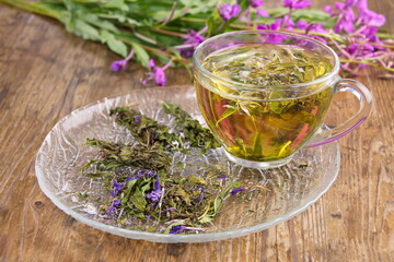 A tea drink made from boiling water, in a glass cup. Flowers and leaves of the fermented plant (Chamerion angustifolium)