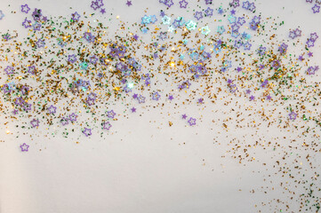 Christmas background. Golden and green confetti and purple glitter stars lie on white plush background. Copy space. Winter holiday. New Year.