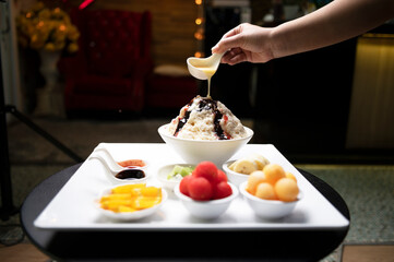 Fresh fruit with scoops of creamy speciality ice cream in assorted flavors with raspberry, berry, blueberry, strawberry, walnut , pistachio, chocolate, sugar cones and a scoop for serving from above