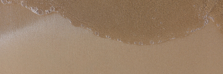 Beach with wet sand and water closeup