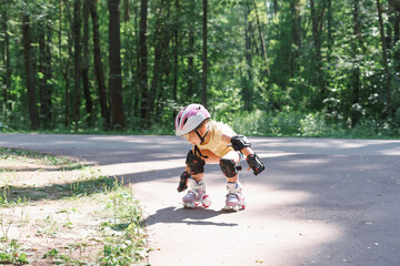 little girl is rollerblading in the park. Kid in protective sportswear
