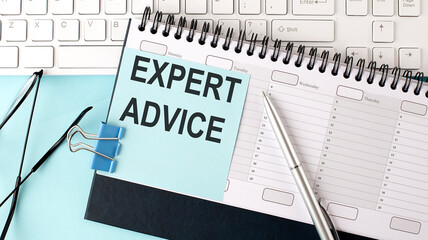 EXPERT ADVICE text on blue sticker on planning and keyboard,blue background