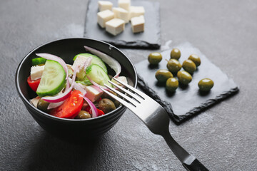 Bowl with tasty Greek salad on dark background, closeup