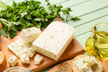 Board with tasty feta cheese, oil and parsley on color wooden background, closeup