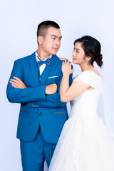 Pre-wedding portrait of a young Asian couple wearing bridal and groom outfits for a pre-wedding photoshoot together showing their love in a white background.