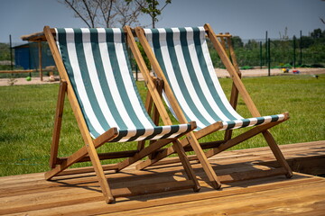 Sun terrace at resort deck chair on vacation, wood flooring and green summer grass background, spa...