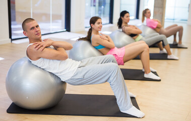 Obraz premium Group of people doing roll ups on fitness balls