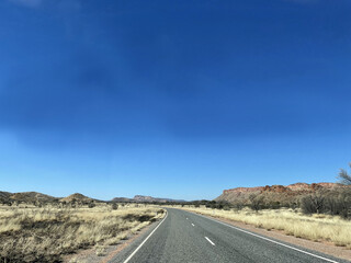 The stunning MacDonnell Ranges, outside Alice Springs, Northern Territory, Australia.  With long roads and open plains with distant mountains.