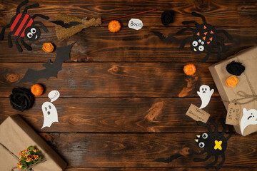 Flat lay Halloween background with decorative pumpkin, ghost, spiders and bats on wooden backdrop....