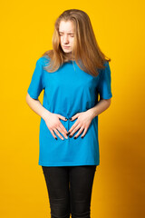 Sad young woman suffers from abdominal stomach pain, touches belly with both hands, has menstruation.