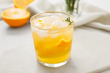 Glass of tasty orange cocktail with rosemary on light background, closeup