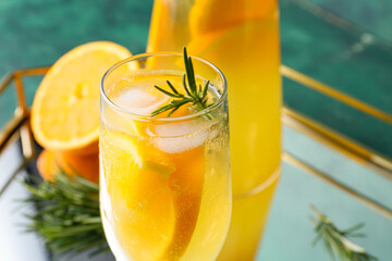 Glass of tasty orange cocktail with rosemary on color background, closeup