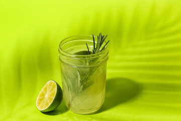 Glass of tasty lime cocktail with rosemary on color background, closeup