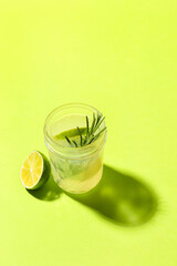 Glass of tasty lime cocktail with rosemary on color background