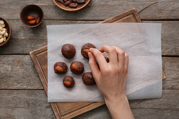 Woman decorating tasty chocolate candies on wooden background
