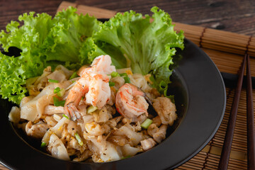 Top view stir fried noodle with chicken and shrimp on wooden table