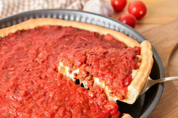 Baking dish with tasty Chicago-style pizza on table, closeup