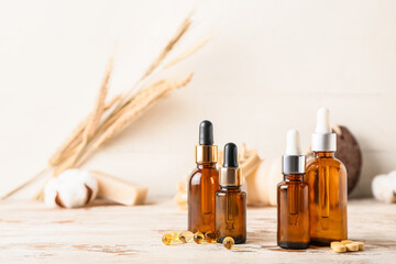 Bottles of cosmetic products and pills on light wooden background