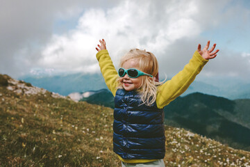 Toddler happy raised hands hiking in mountains family travel vacations healthy lifestyle 2 years...