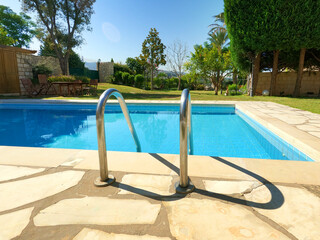 Beautiful old swimming pool in summer season. Blue tiles. Garden and pool view. Travel destination for summer vacations