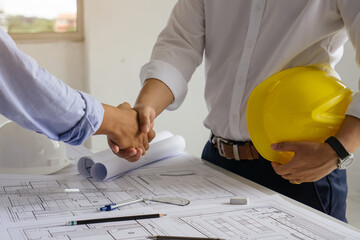 Architect and engineer shaking hands after finish an agreement in the office construction site, success collaboration concept.
