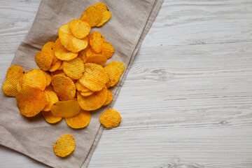 Ruffled Cheese Potato Chips in a Bowl on a white wooden background, top view. Flat lay, overhead, from above. Space for text.