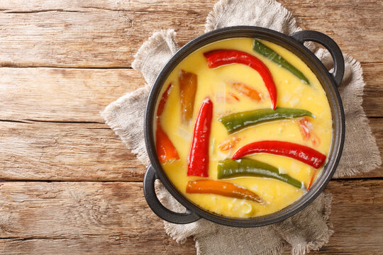 Spicy Ema datshi the national dish of Bhutan is an easy to make hearty soup with chilli peppers and cheese closeup in the pan on the table. horizontal top view from above