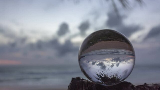.time lapse beautiful cloud moving and red sunset inside crystal ball placed on a branch beside the beach..crystal ball on a branch shaking while windy..Unique and creative travel and nature idea.