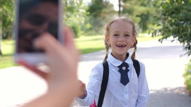 Mother Taking Photos with Smartphone of her Happy Daughter before School. Slow Motion. First Day at School Concept