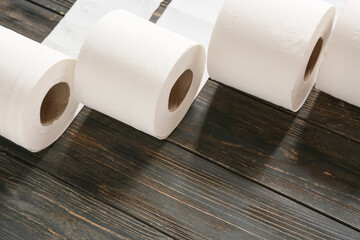 Rolls of toilet paper on dark wooden background