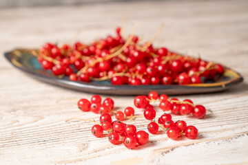 View of red currant on beautifull plate on wooden table. Bunch of fresh red currants on a plate