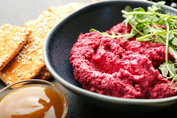 Bowl with tasty beet hummus, fresh sprouts, sauce and crackers, closeup