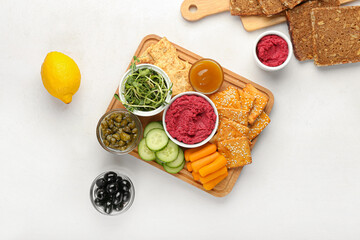 Fototapeta na wymiar Board with tasty beet hummus and snacks on light background