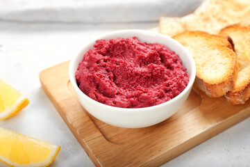 Bowl with tasty beet hummus and toasts on light background, closeup