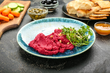 Plate with tasty beet hummus and fresh sprouts on dark background
