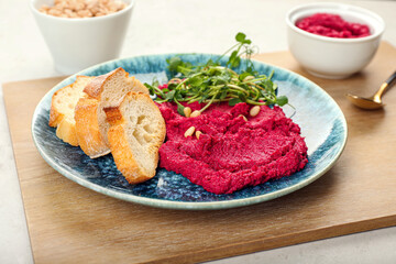 Plate with tasty beet hummus, fresh sprouts and bread on light background