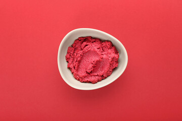 Bowl with tasty beet hummus on color background