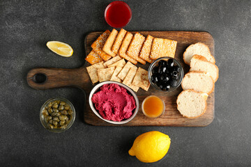 Composition with tasty beet hummus, snacks and sauces on dark background